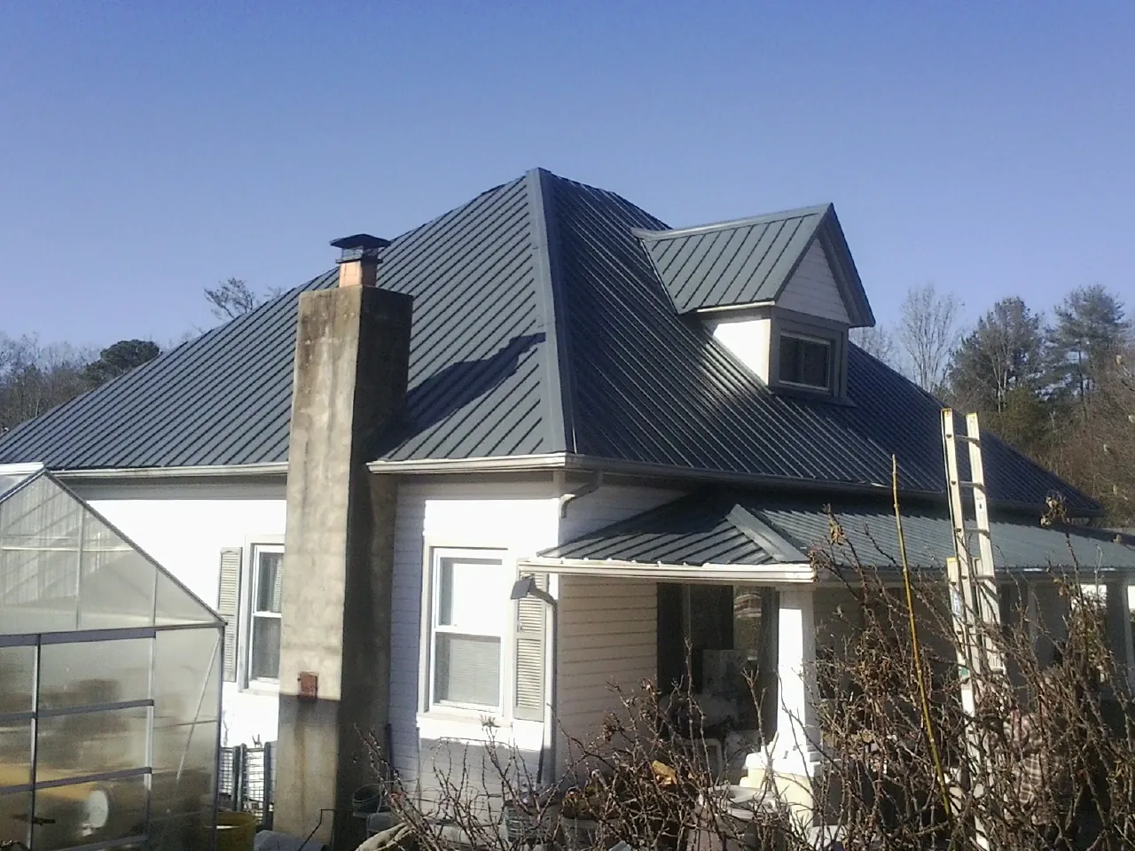 Dark blue standing seam metal roof on a white farmhouse with dormer — Slate & Tile Roof Repair by Roofing Brothers in Page