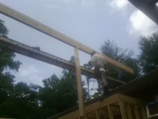 Carpenter setting a ridge beam over a new addition frame — Ice Dam Removal by Roofing Brothers in Page