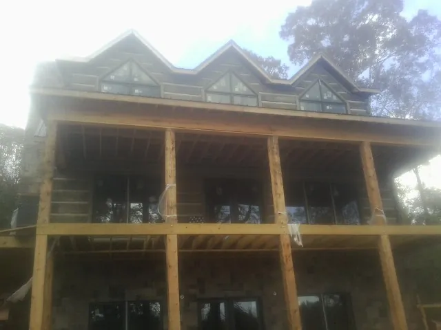 Dormers and porch framing on a large log home under construction — Roof Coating work by our crew in Page