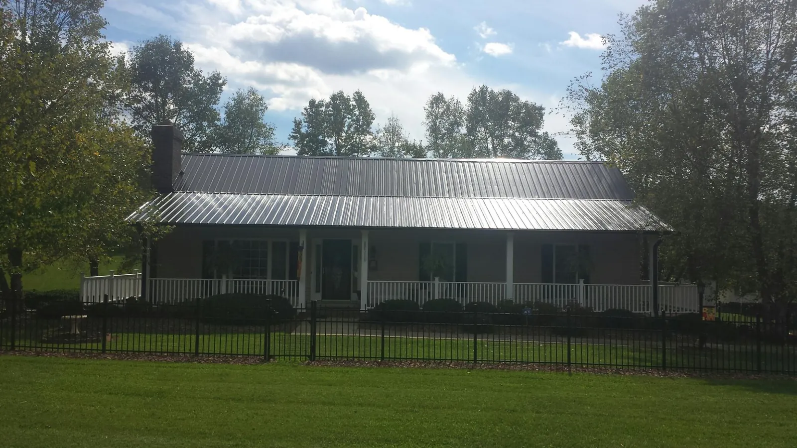 Gray metal roof on a brick ranch with a full width front porch — Gutter Guard Installation work by our crew in Page