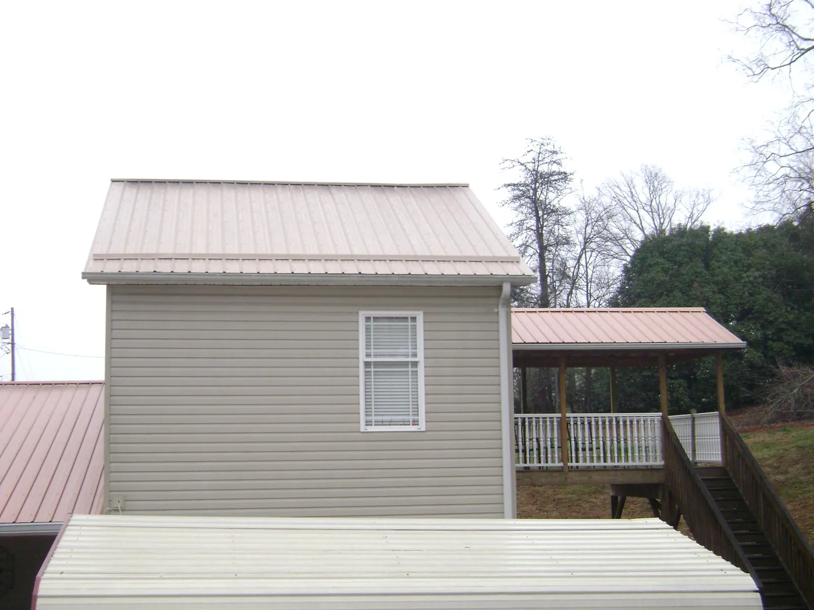 Tan metal roofs on a two story addition and attached porch, from a Roof Replacement job in Page