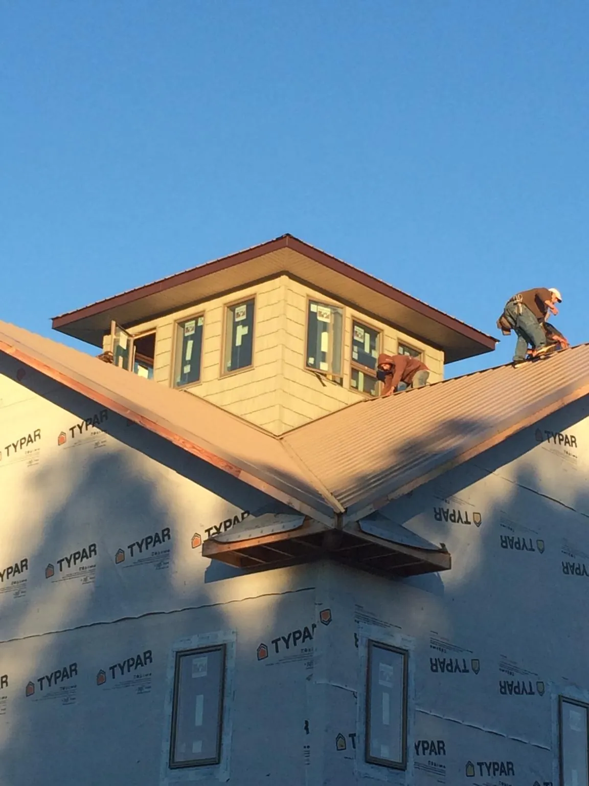 Roofers working around a rooftop cupola on a new metal roof at sunset — Roof Waterproofing in Page by Roofing Brothers